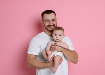 Photo of Father with his cute baby on pink background