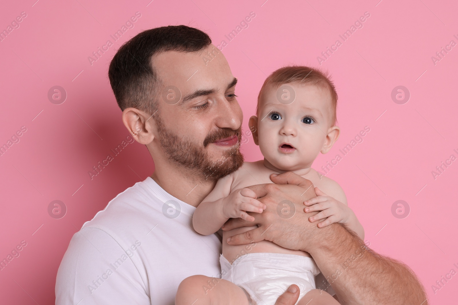 Photo of Father with his cute baby on pink background