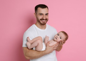 Father with his cute baby on pink background