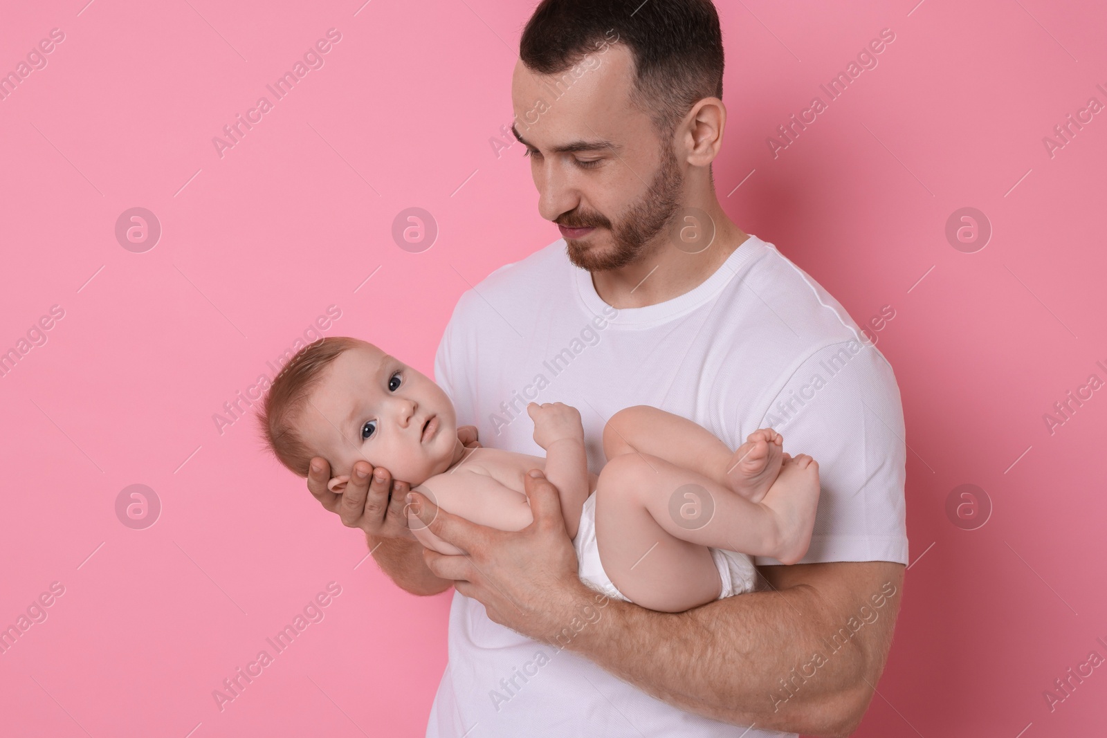 Photo of Father with his cute baby on pink background