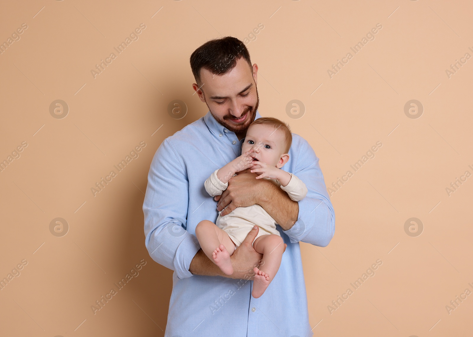 Photo of Father with his cute baby on beige background