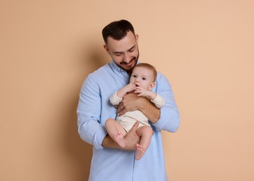 Photo of Father with his cute baby on beige background