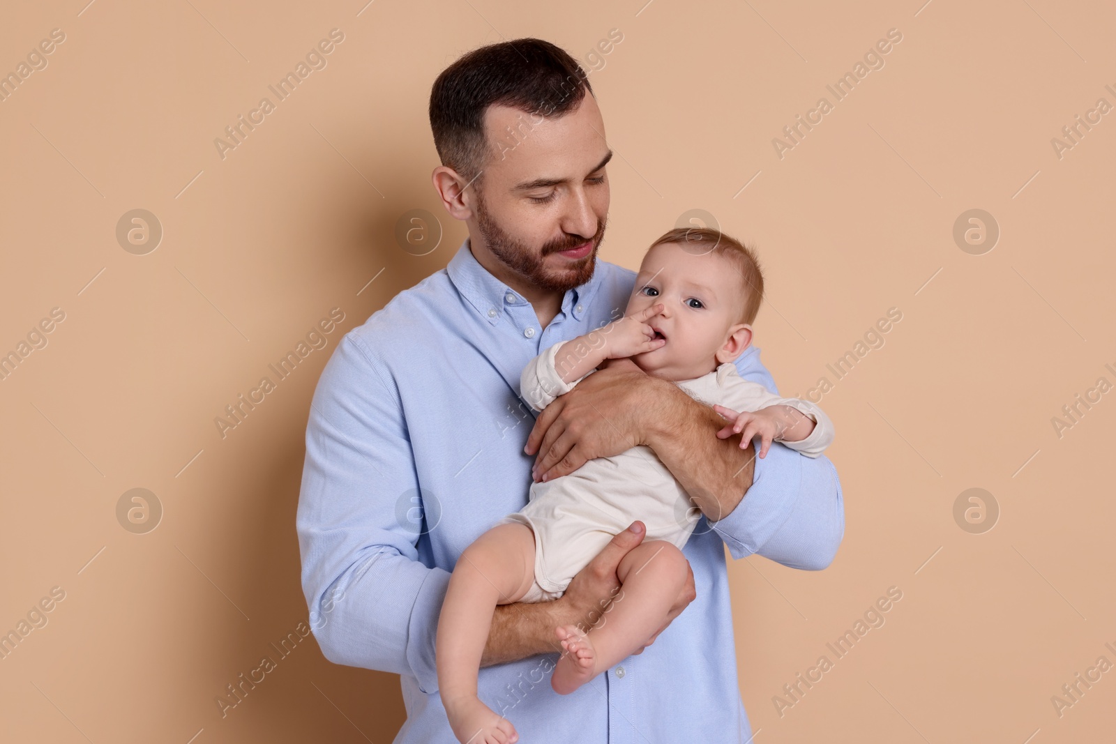 Photo of Father with his cute baby on beige background