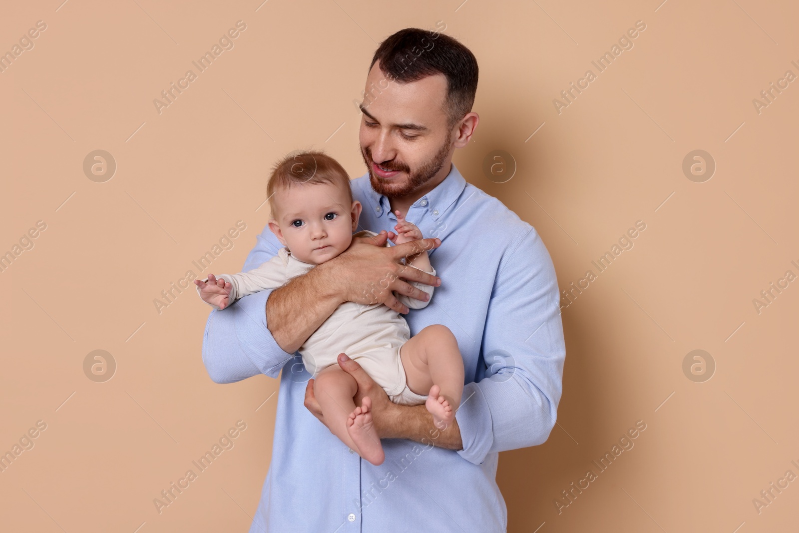 Photo of Father with his cute baby on beige background