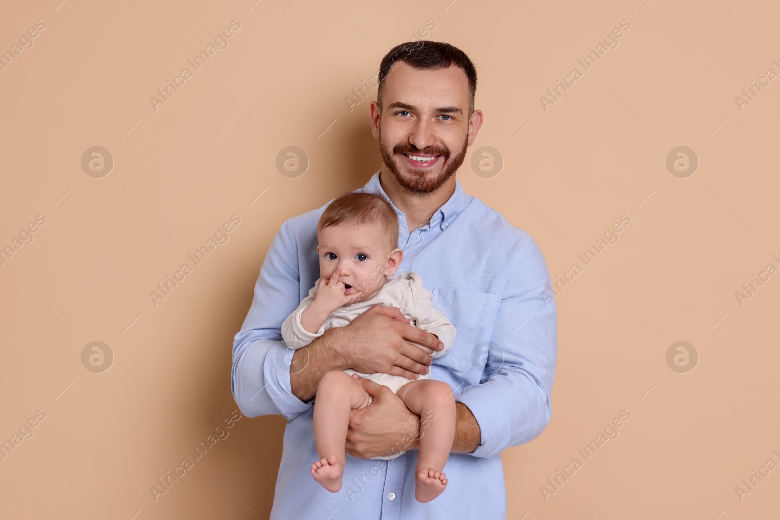 Photo of Father with his cute baby on beige background