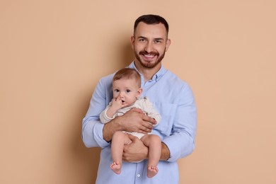 Father with his cute baby on beige background