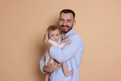 Photo of Father with his cute baby on beige background