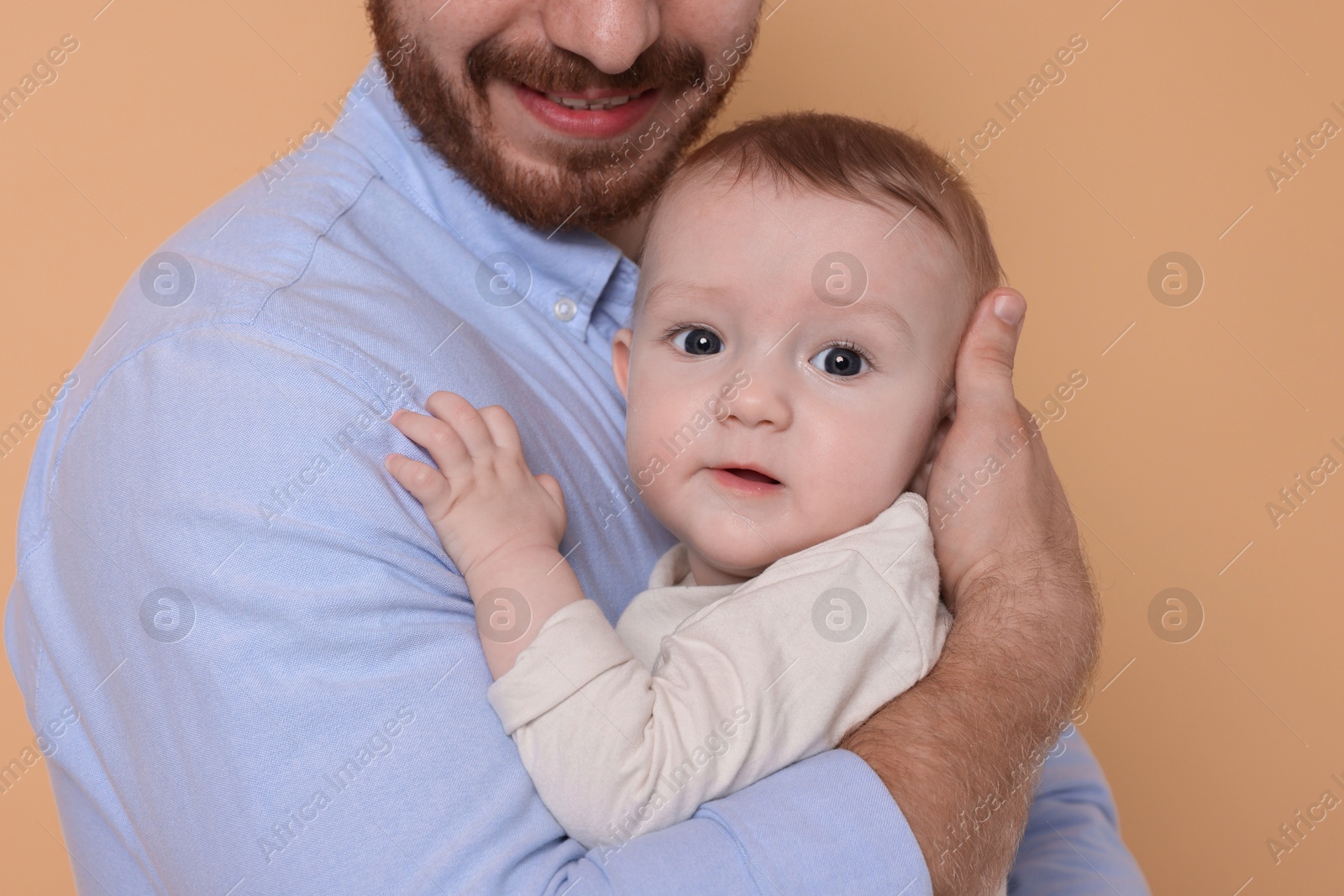 Photo of Father with his cute baby on beige background