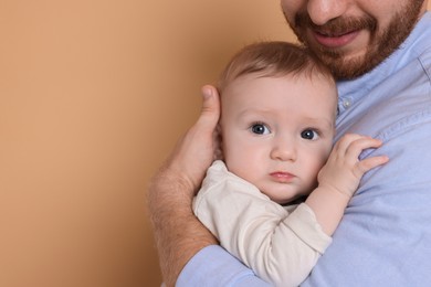 Father with his cute baby on beige background, space for text