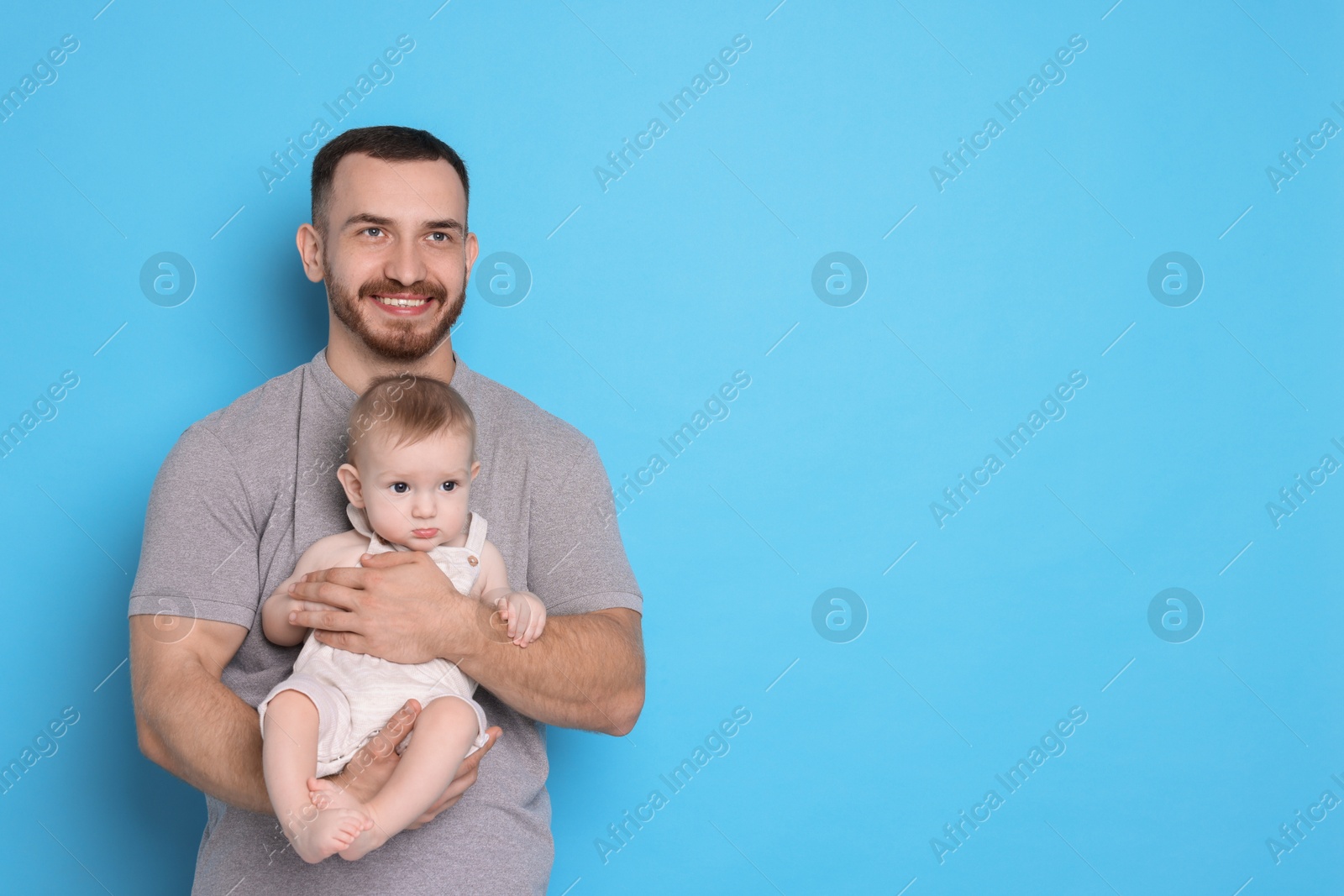 Photo of Father with his cute baby on light blue background, space for text