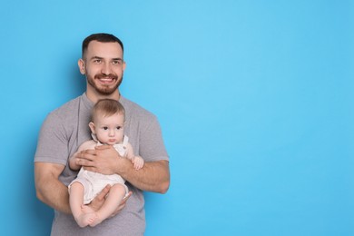 Photo of Father with his cute baby on light blue background, space for text