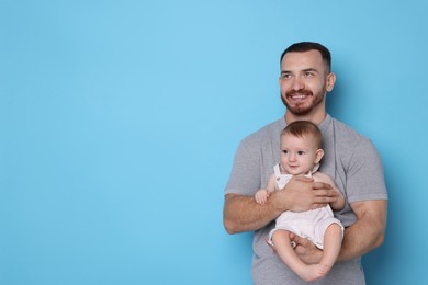 Photo of Father with his cute baby on light blue background, space for text