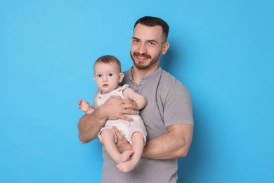 Photo of Father with his cute baby on light blue background