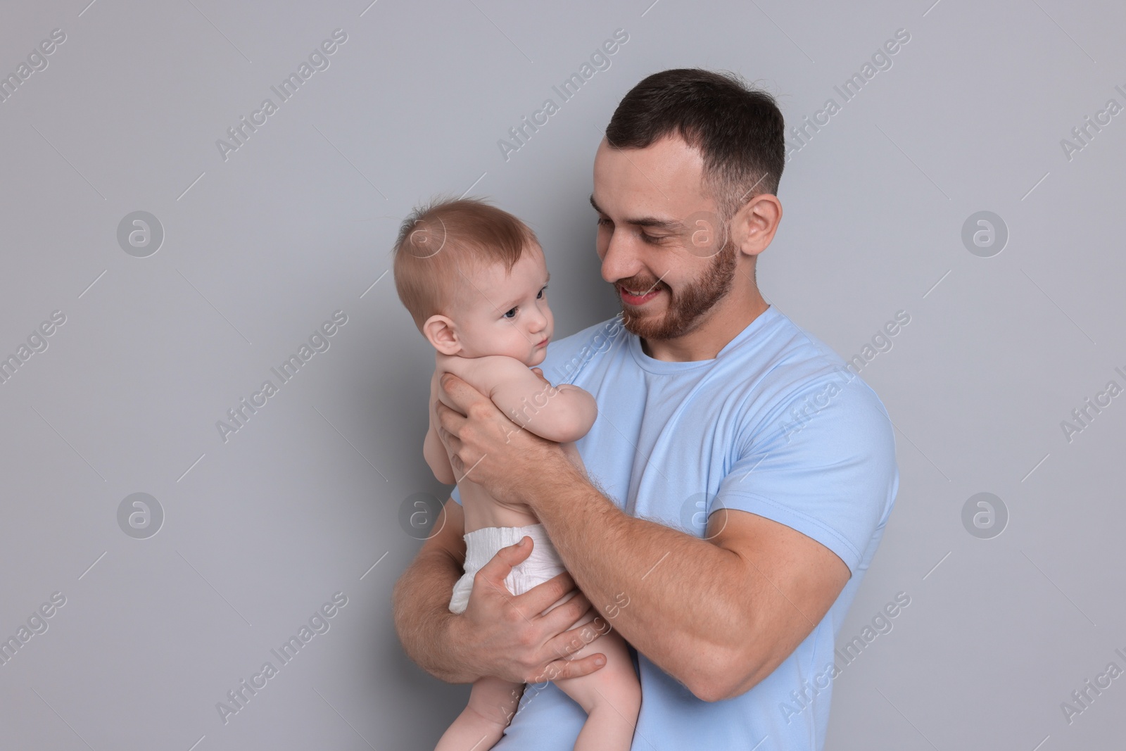 Photo of Father with his cute baby on grey background