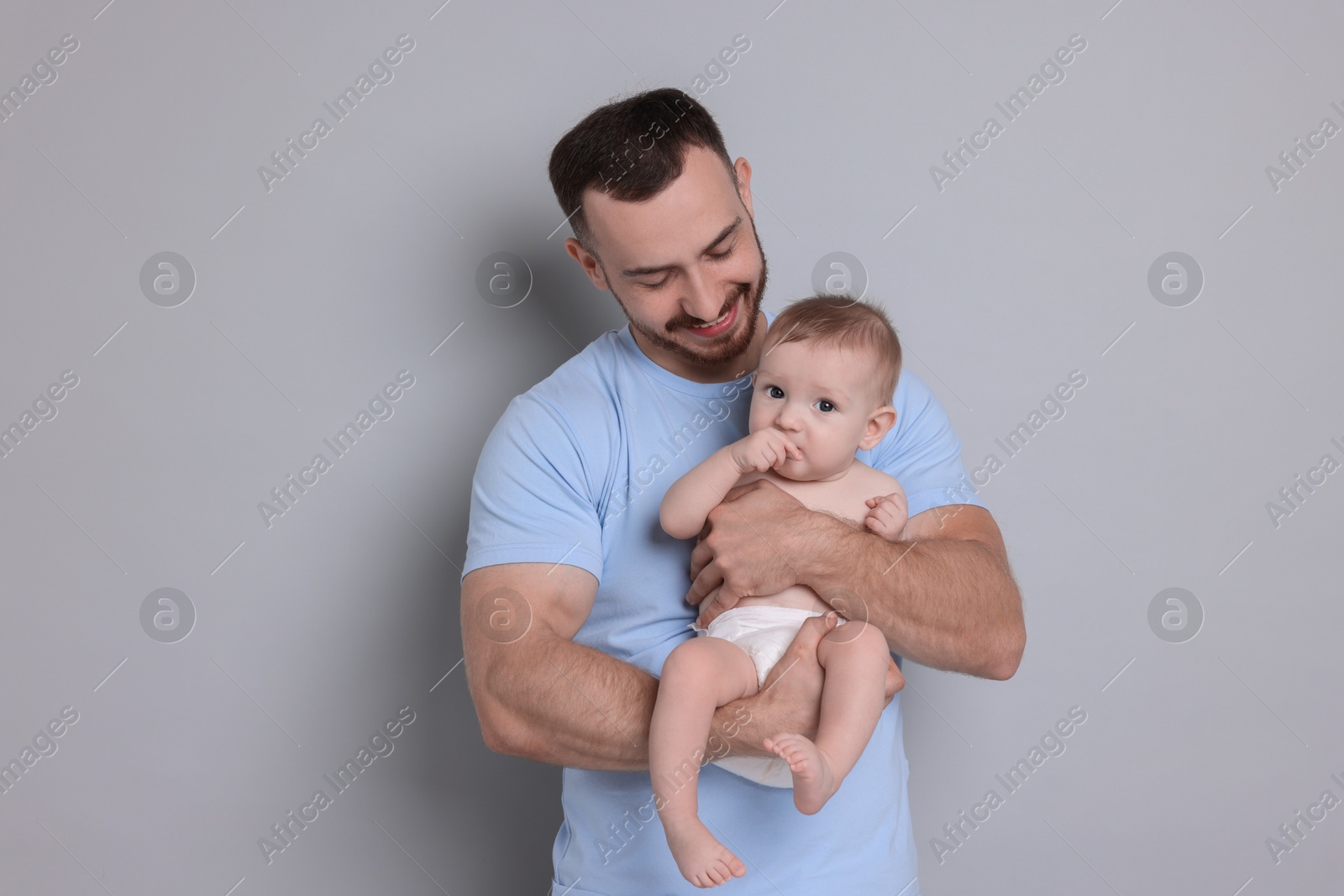 Photo of Father with his cute baby on grey background