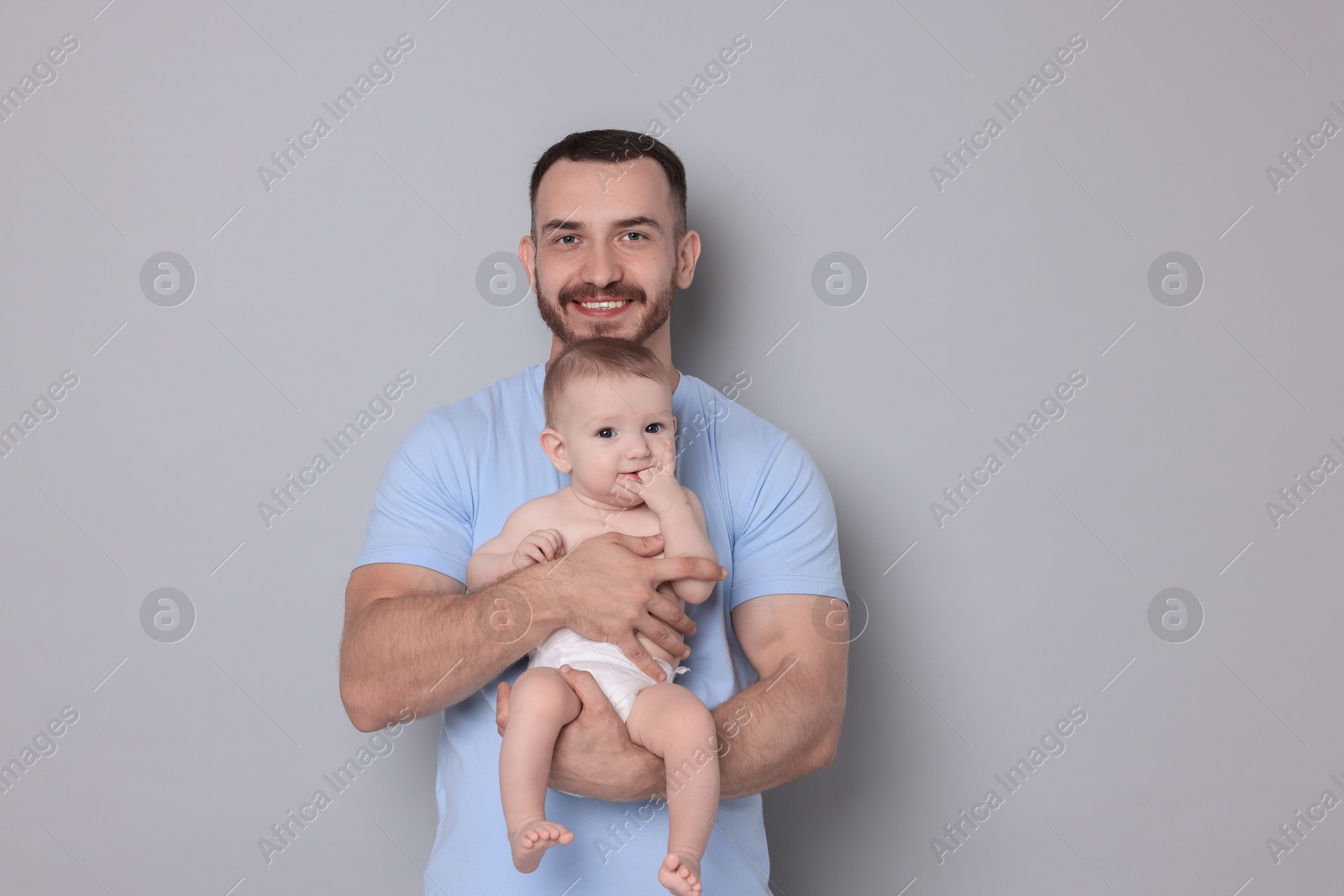 Photo of Father with his cute baby on grey background