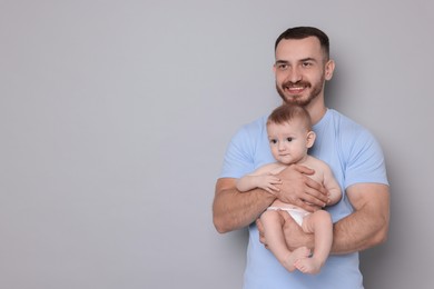 Photo of Father with his cute baby on grey background, space for text