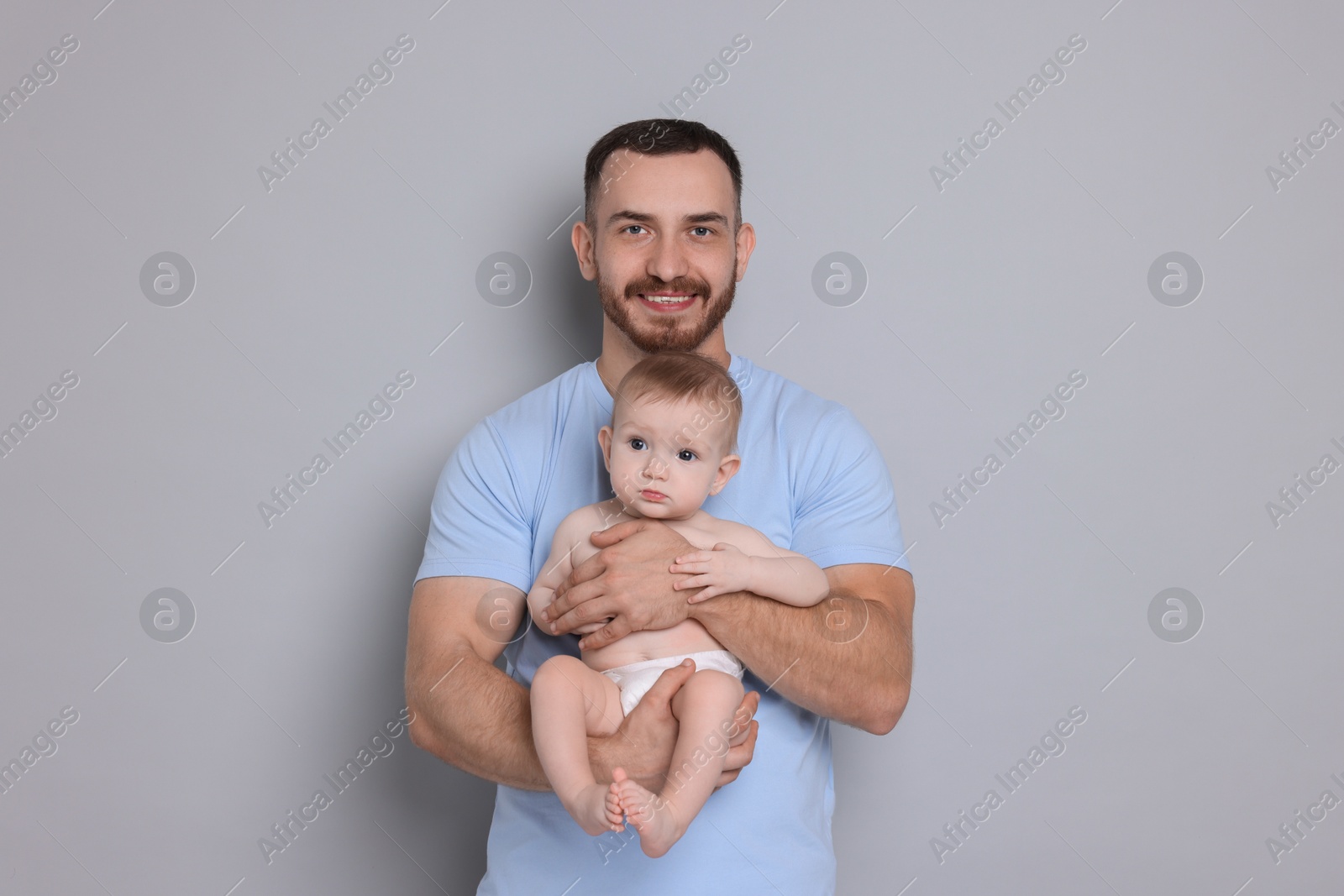 Photo of Father with his cute baby on grey background