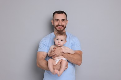 Photo of Father with his cute baby on grey background