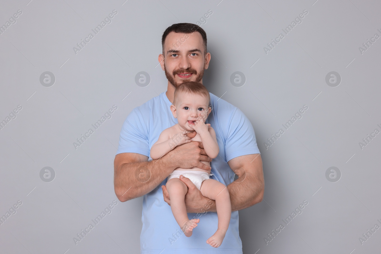 Photo of Father with his cute baby on grey background