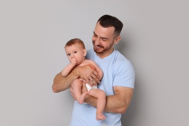 Photo of Father with his cute baby on grey background