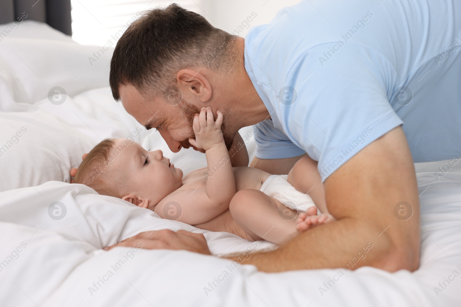 Photo of Father with his cute baby on bed at home