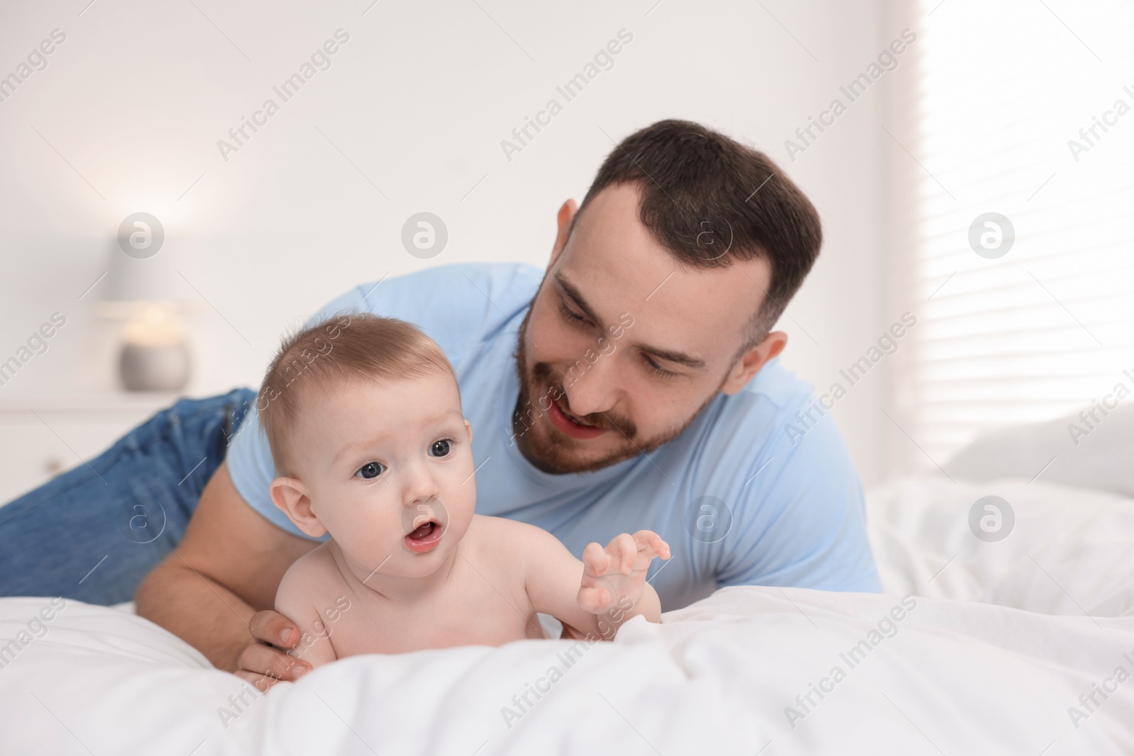 Photo of Father with his cute baby on bed at home