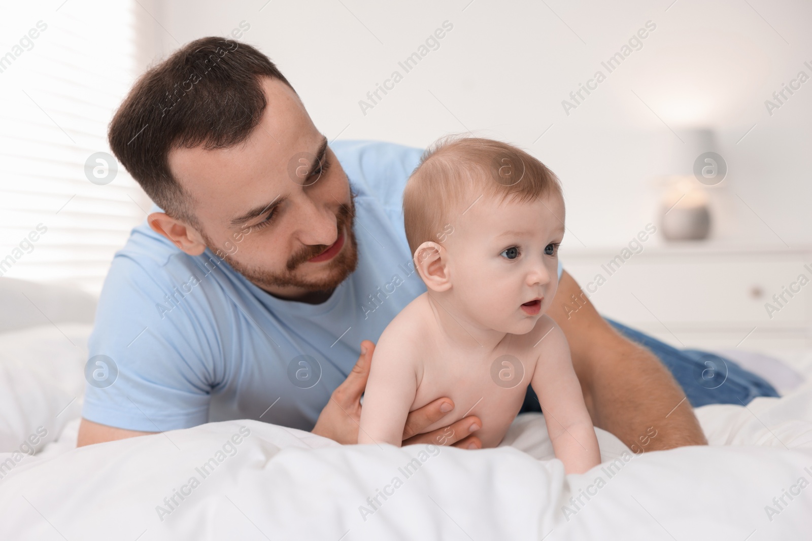 Photo of Father with his cute baby on bed at home