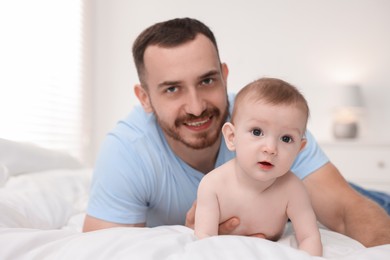 Photo of Father with his cute baby on bed at home