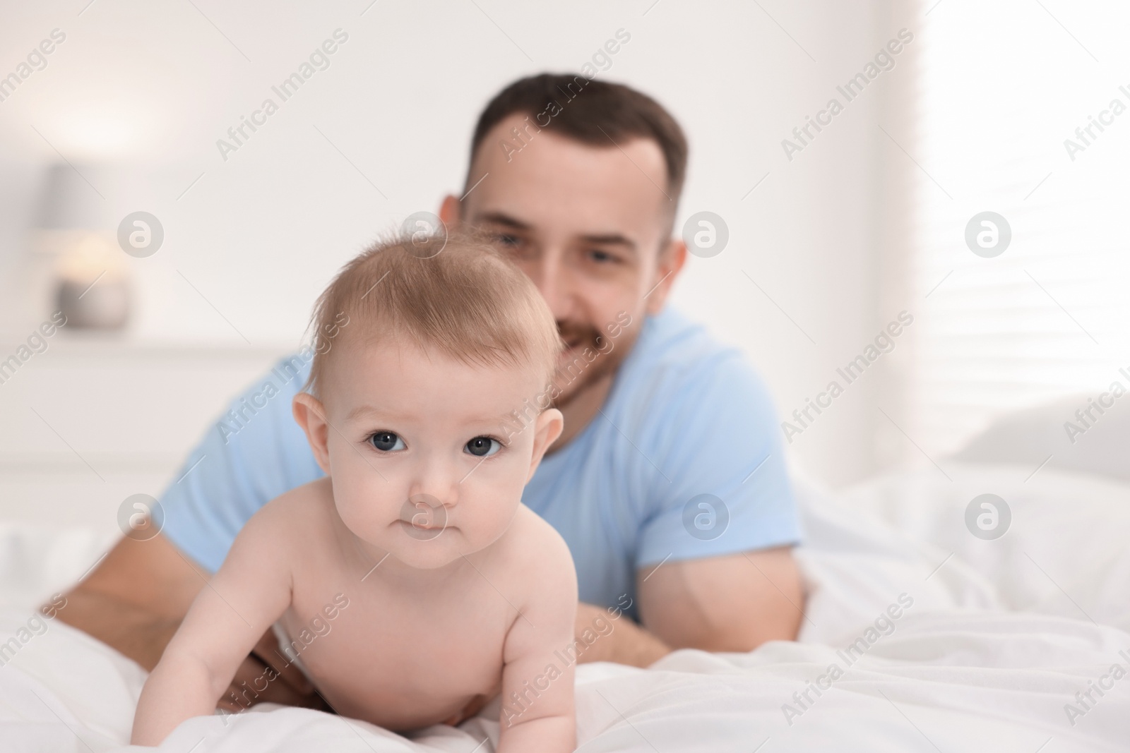 Photo of Father with his cute baby on bed at home, selective focus