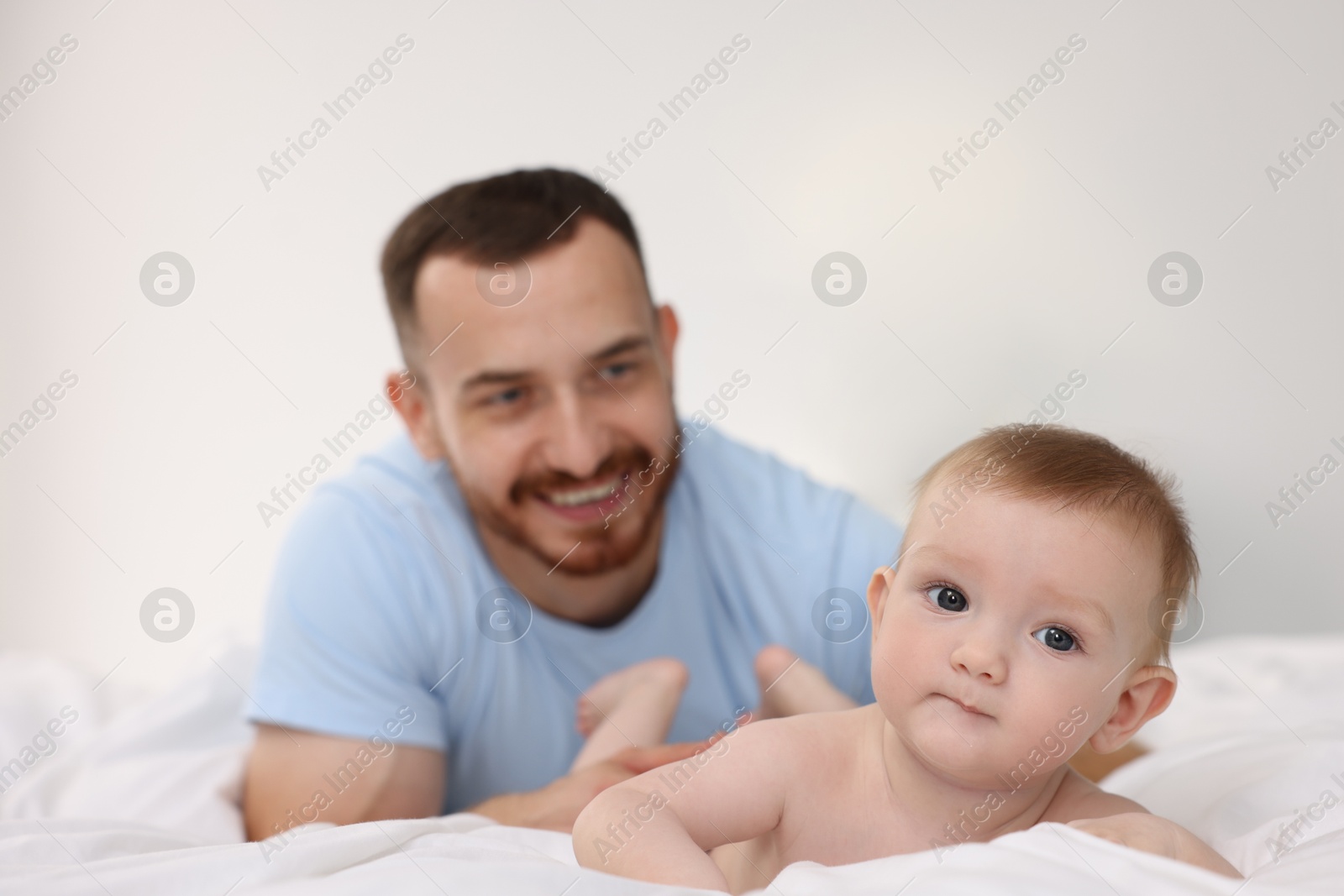 Photo of Father with his cute baby on bed at home, selective focus