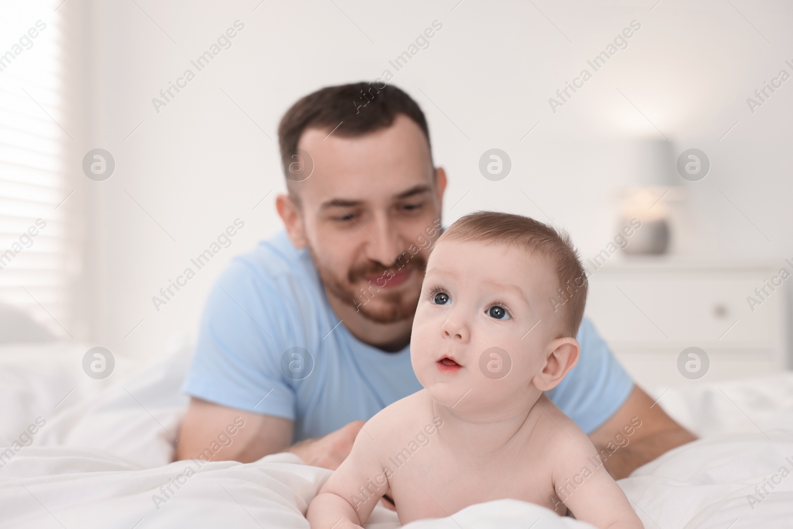 Photo of Father with his cute baby on bed at home, selective focus