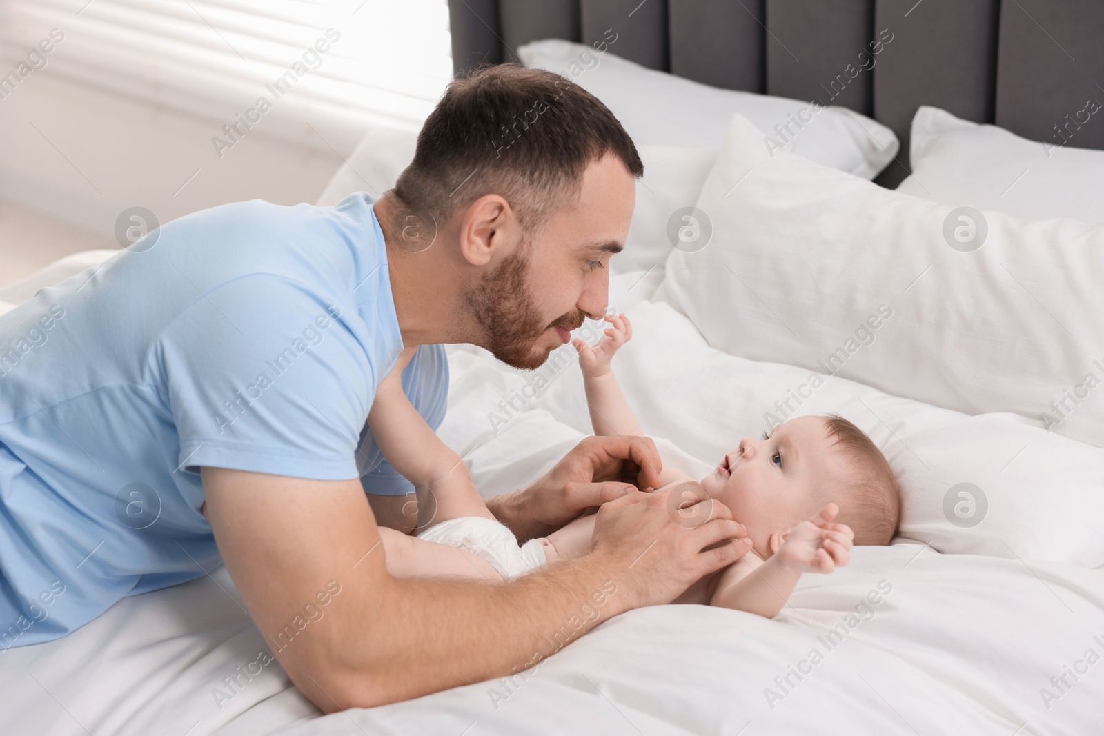 Photo of Father with his cute baby on bed at home