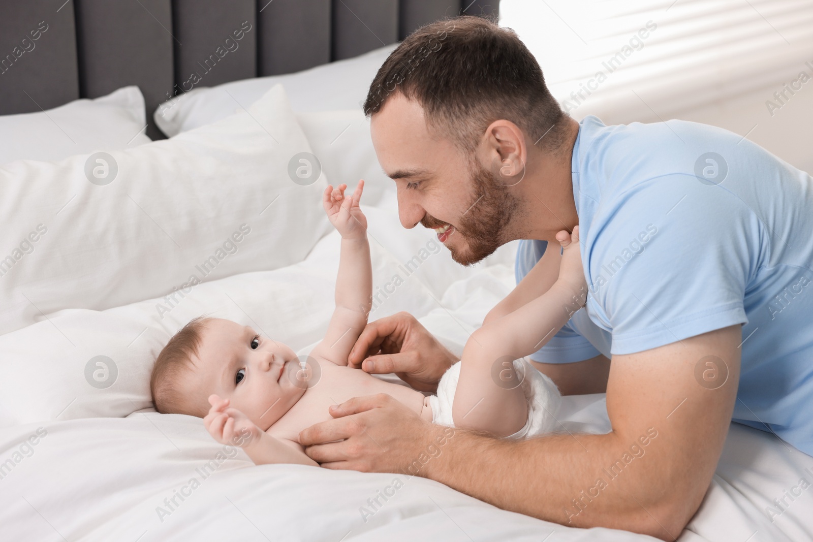 Photo of Father with his cute baby on bed at home