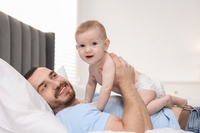 Photo of Father with his cute baby on bed at home