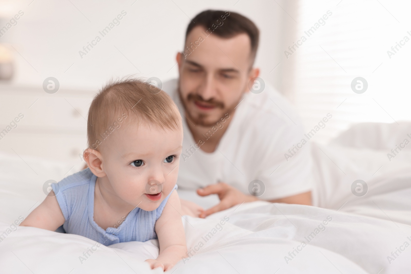 Photo of Father with his cute baby on bed at home, selective focus