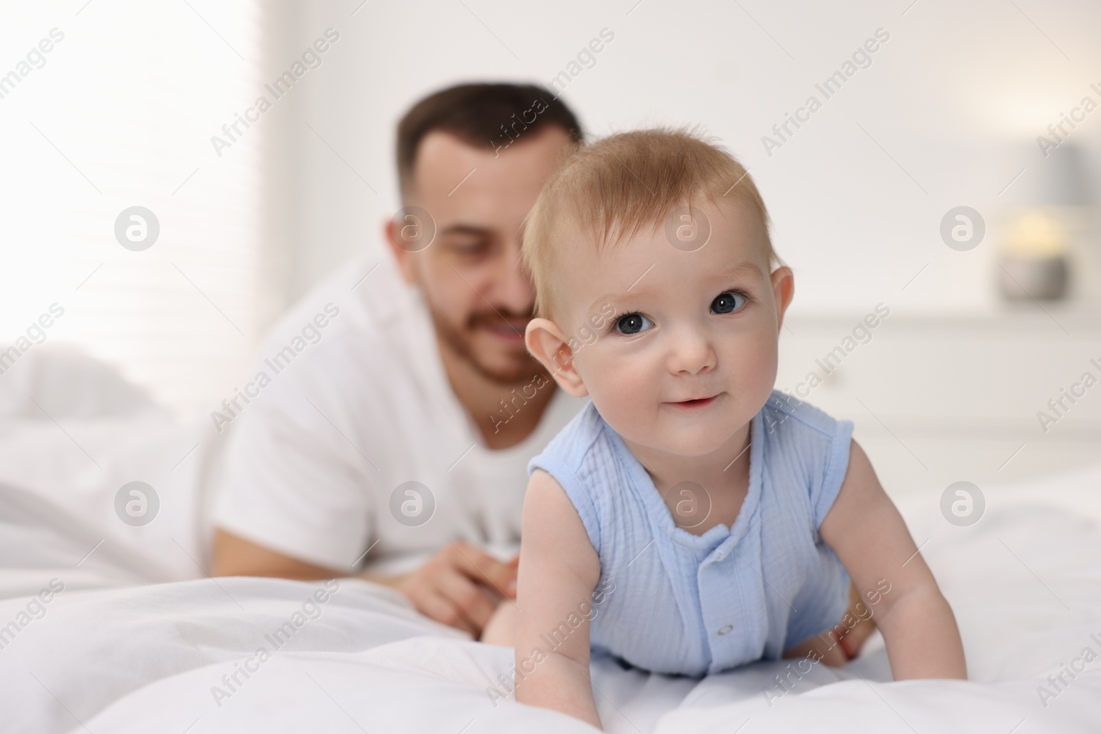 Photo of Father with his cute baby on bed at home, selective focus