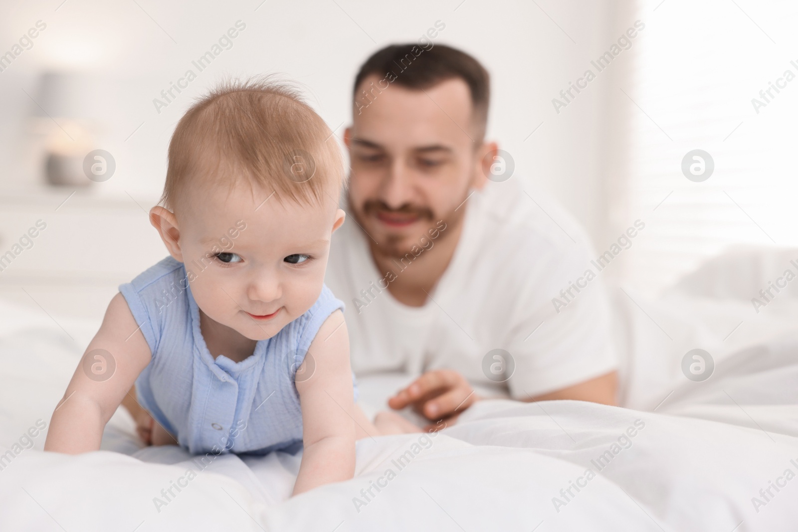 Photo of Father with his cute baby on bed at home, selective focus