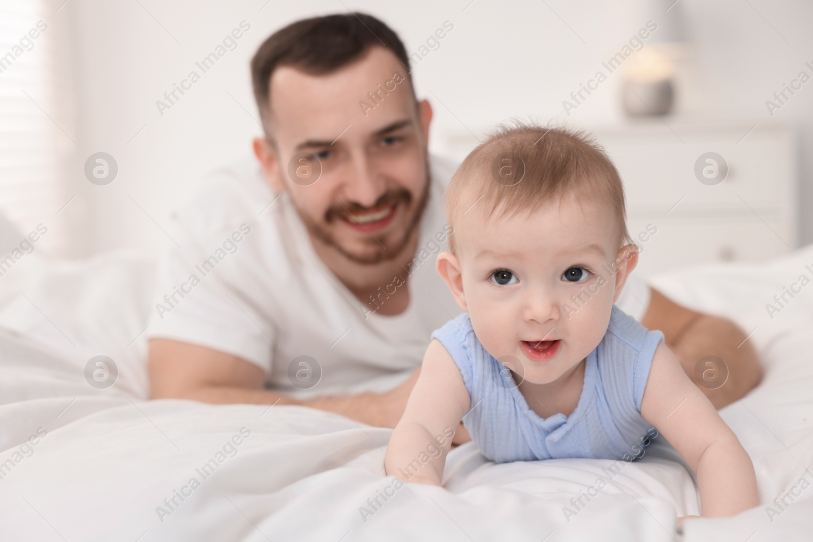 Photo of Father with his cute baby on bed at home, selective focus