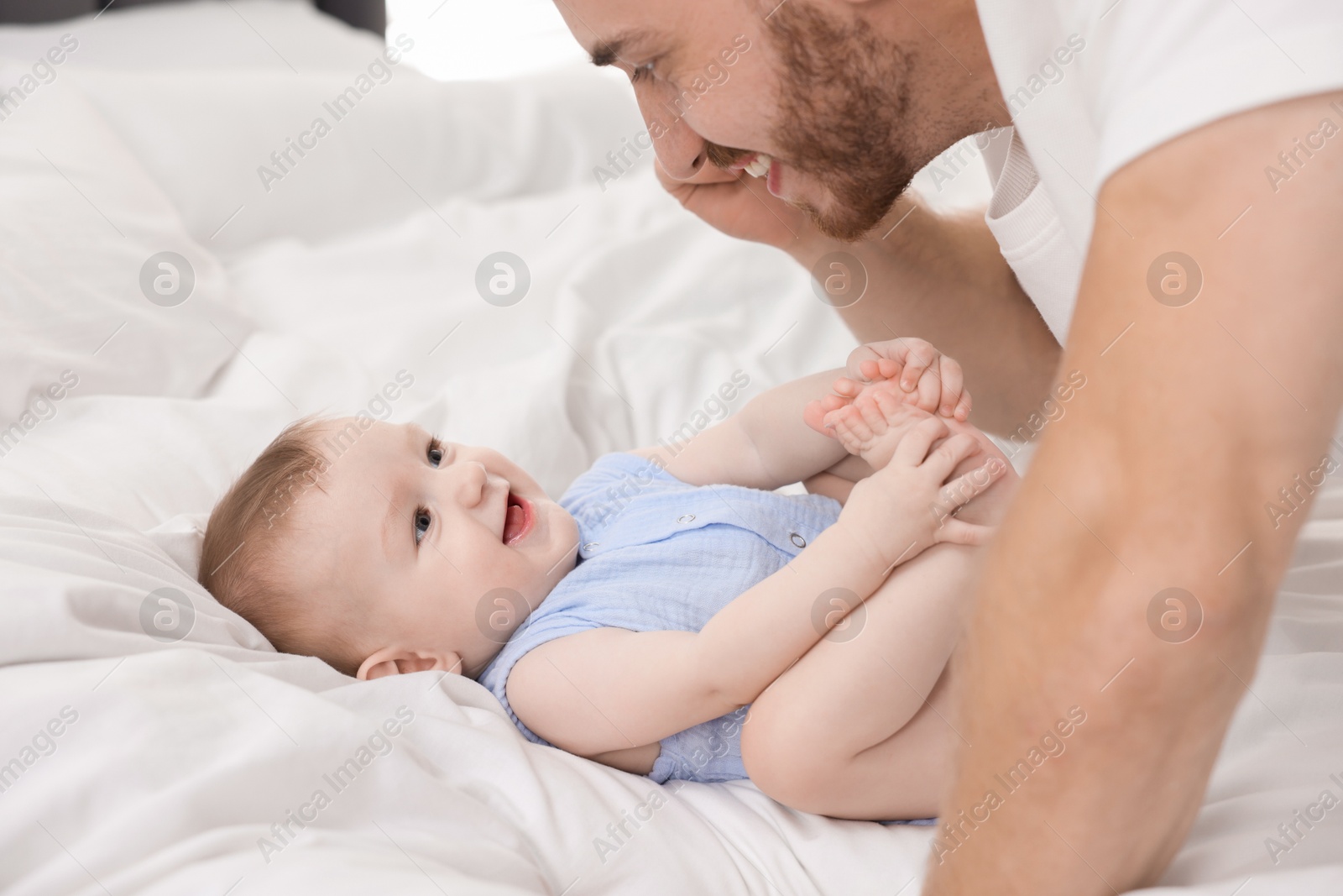 Photo of Father with his cute baby on bed at home