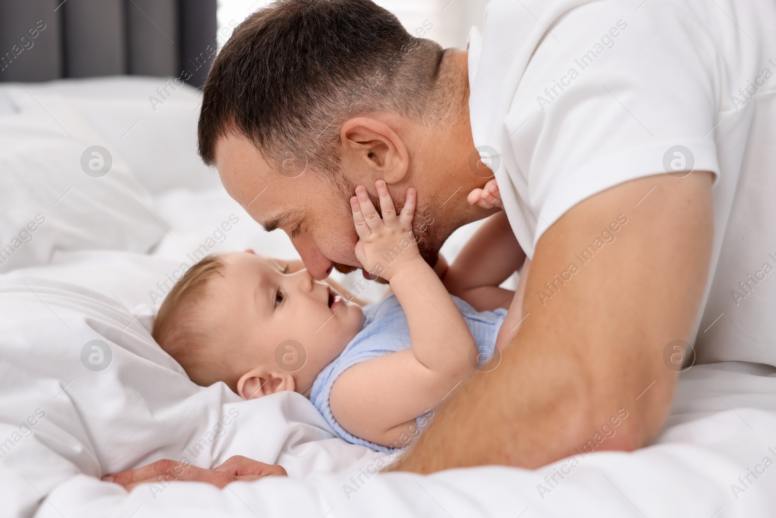 Photo of Father with his cute baby on bed at home