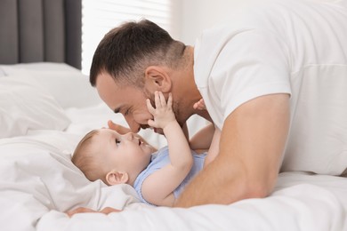 Photo of Father with his cute baby on bed at home