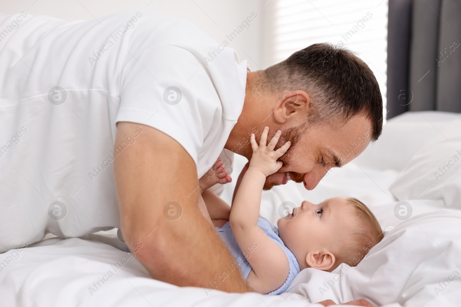 Photo of Father with his cute baby on bed at home