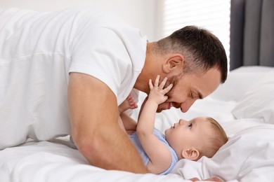 Father with his cute baby on bed at home