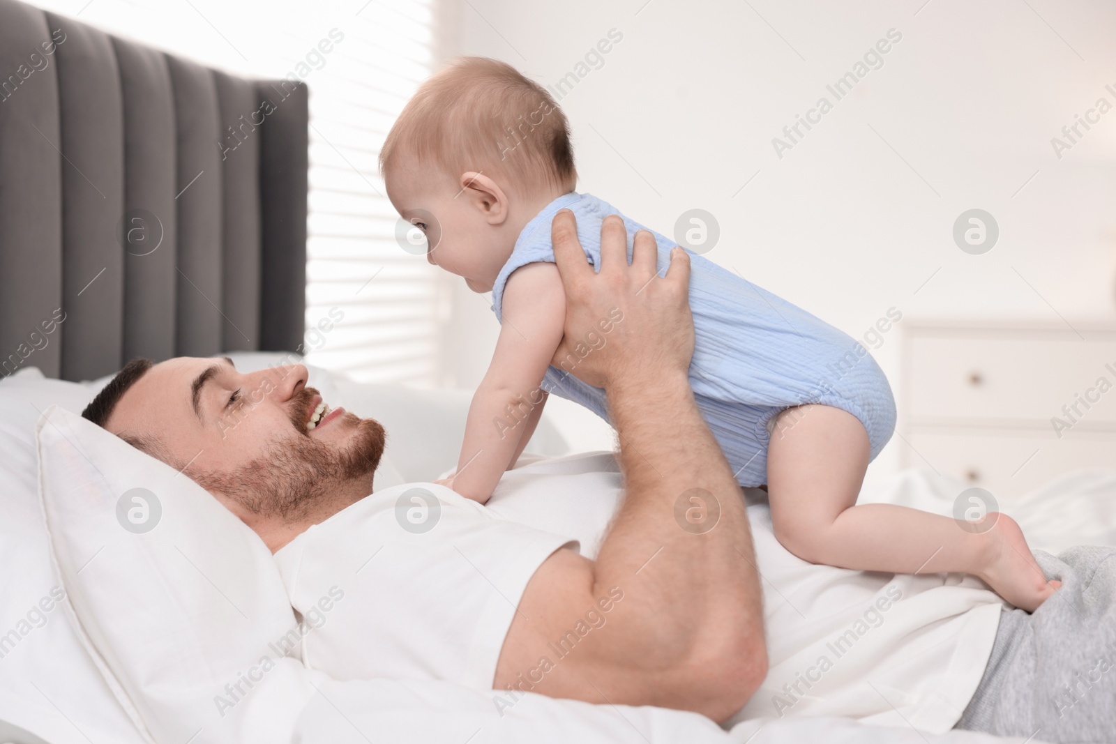 Photo of Father with his cute baby on bed at home