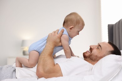 Photo of Father with his cute baby on bed at home