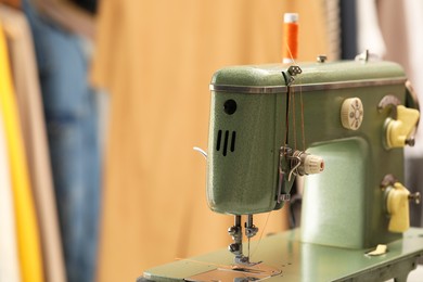 Photo of Vintage sewing machine with thread on blurred background, closeup. Space for text