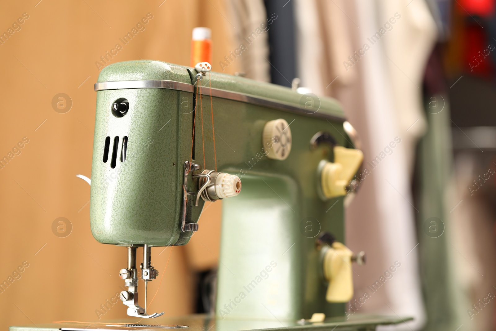 Photo of Vintage sewing machine with thread on blurred background, closeup