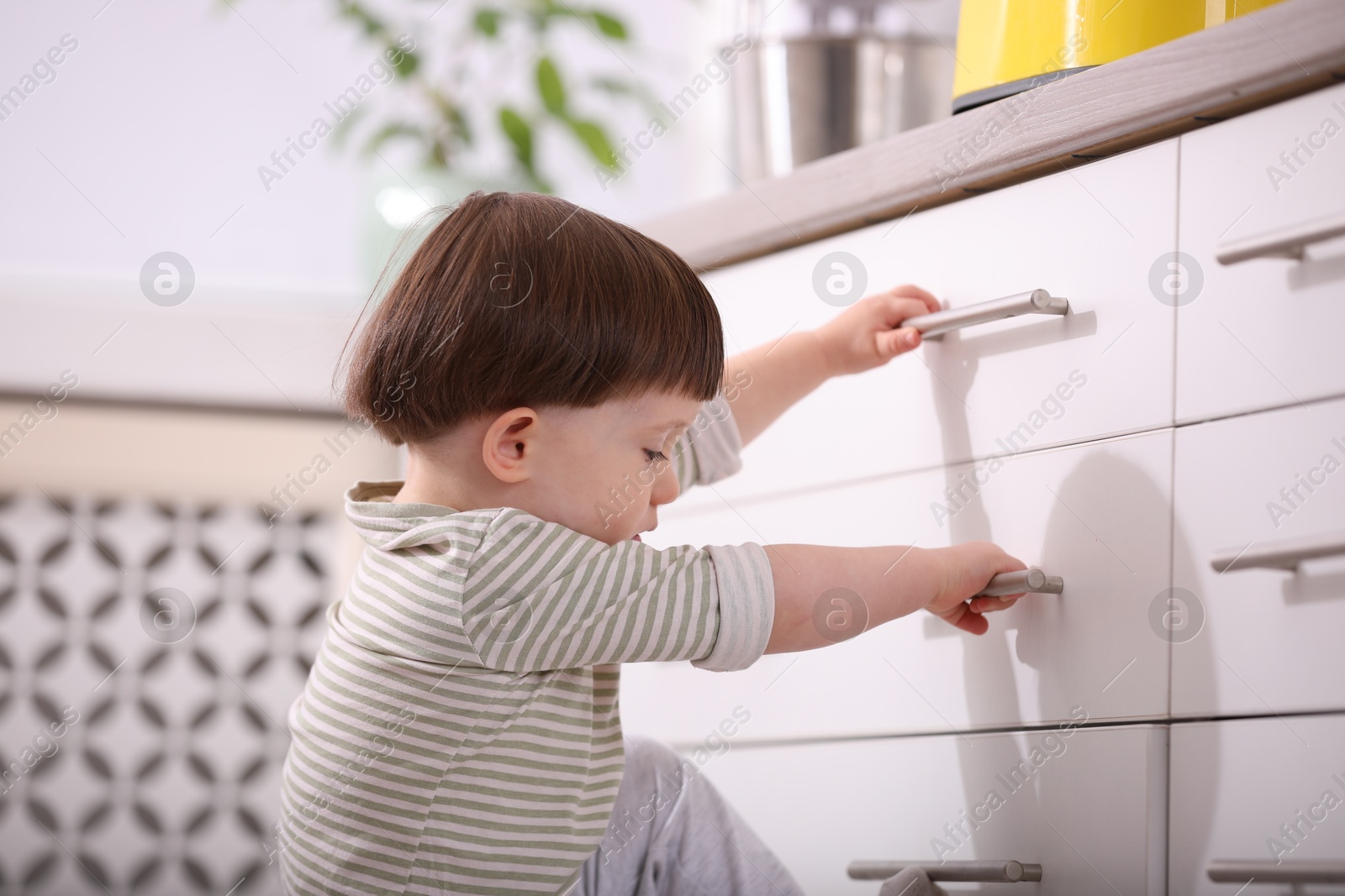 Photo of Little boy near kitchen counter indoors. Dangerous situation