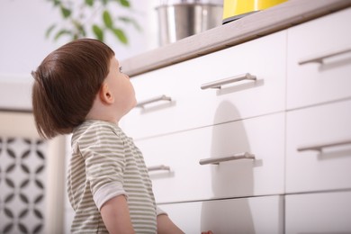 Photo of Little boy near kitchen counter indoors. Dangerous situation